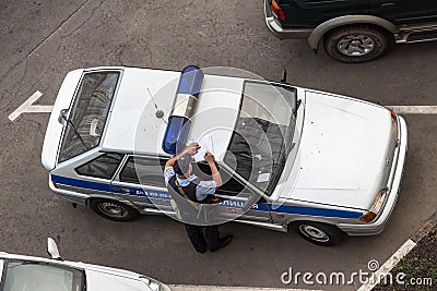 Police officer makes an entry leaning on the car roof Editorial Stock Photo